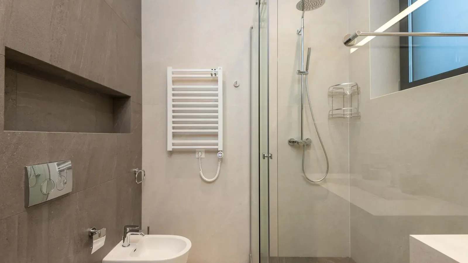 Pogled prema vratima – radijator, tuš i umivaonik